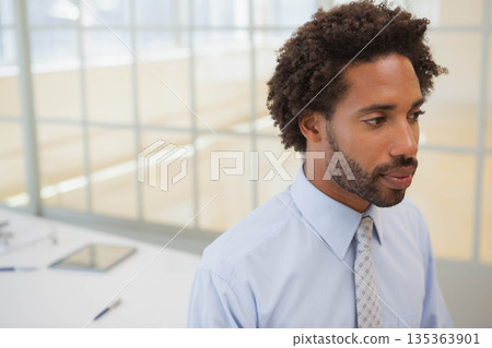 African American man wearing shirt and tie, reviewing papers at office desk with tablet, copy space African American man wearing shirt and tie, reviewing papers at office desk with tablet, copy space 135363901