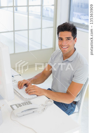 Man typing on keyboard at office desk using computer monitor and telephone, copy space 135363909