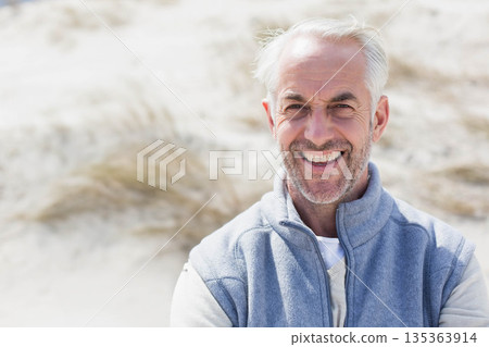 Senior man smiling and standing at coastal sand dunes wearing grey fleece vest, copy space Senior man smiling and standing at coastal sand dunes wearing grey fleece vest, copy space 135363914
