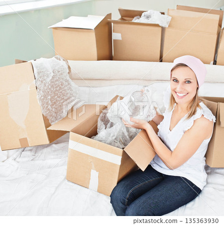 Woman holding glass jar with bubble wrap on white couch among moving boxes, copy space 135363930