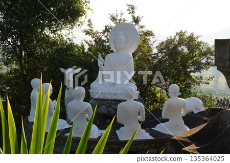 Several white, old temple statues in a blooming garden.Statues of the old temple. Several white, old temple statues in a blooming garden.Statues of the old temple. 135364025