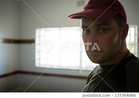 Red baseball cap and yellow lanyard are hanging near bright barred window, above wooden trim Red baseball cap and yellow lanyard are hanging near bright barred window, above wooden trim 135364066