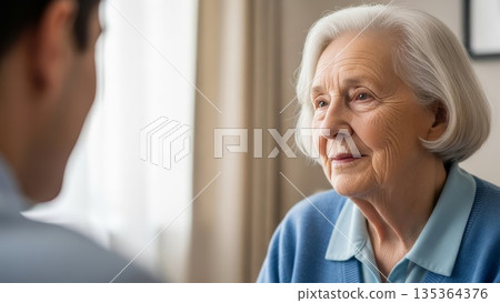 Senior caucasian woman having conversation with healthcare professional during medical consultation at home elderly care visit 135364376