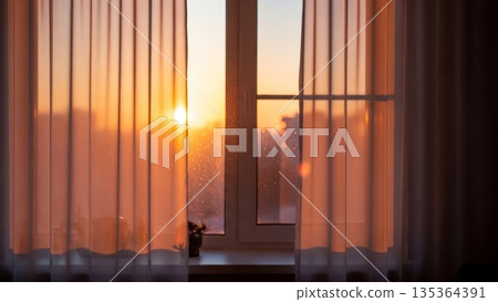 Warm sunset golden hour light streaming through open window with orange curtains and water droplets on glass creating cozy interior atmosphere 135364391