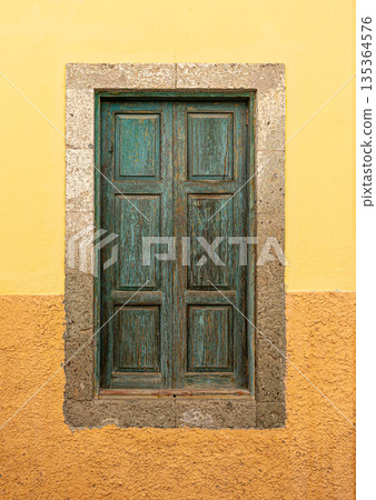 Teal wooden window shutters on yellow wall Teal wooden window shutters on yellow wall 135364576