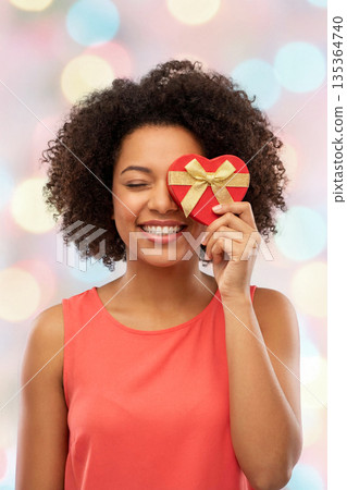 Smiling woman with heart gift box 135364740