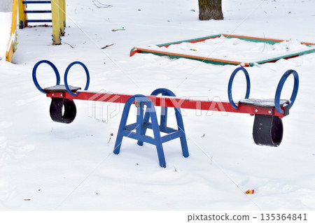 There is snow on the children's swings. 135364841