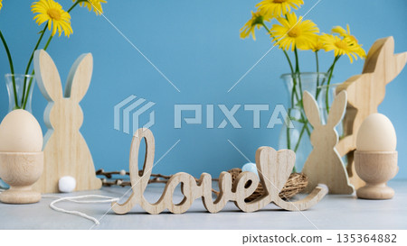 Wooden word LOVE with bunny figures eggs and fresh flowers. Easter composition content still life. Christian symbols of spring 135364882