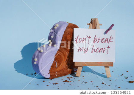 DON'T BREAK MY HEART saying pun joke on paper note card Heart shaped blueberry flavor croissant on blue background with copy space. Puff pastry new trendy sweet dessert bakery. Creamy dough DON'T BREAK MY HEART saying pun joke on paper note card Heart shaped blueberry flavor croissant on blue background with copy space. Puff pastry new trendy sweet dessert bakery. Creamy dough 135364931