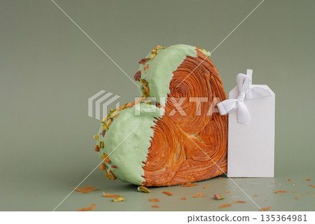 Empty paper note template mock up Delicious fresh croissant topped with Matcha Green Tea flavor Ganache. Creation unique heart shape bakery. Puff pastry holiday love gift present idea Valentine's day 135364981