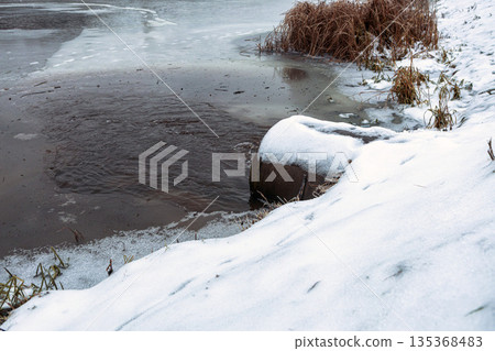 Liquid waste empties from a pipe into flowing river water. 135368483