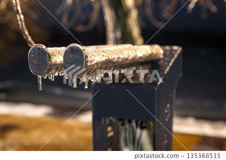 Two metal pipes covered in ice and frost during evening. Cold industrial winter scene. Two metal pipes covered in ice and frost during evening. Cold industrial winter scene. 135368515