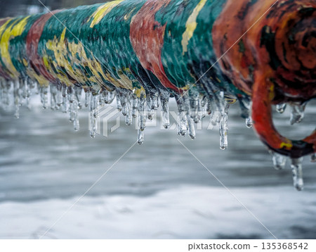 Close-up of a colorful metal fence coated in ice and frost. Close-up of a colorful metal fence coated in ice and frost. 135368542