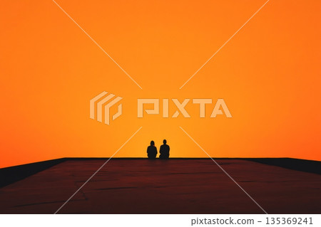 Silhouetted couple savoring a vibrant orange sunset while relaxing on a rooftop, embracing the romance of the urban skyline at dusk 135369241