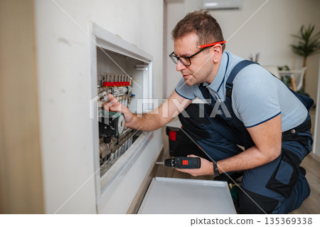 Adult man repairing underfloor heating system at home 135369338