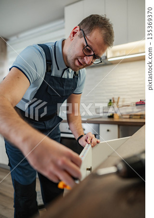 Handyman measuring kitchen cabinet for home improvement project 135369370