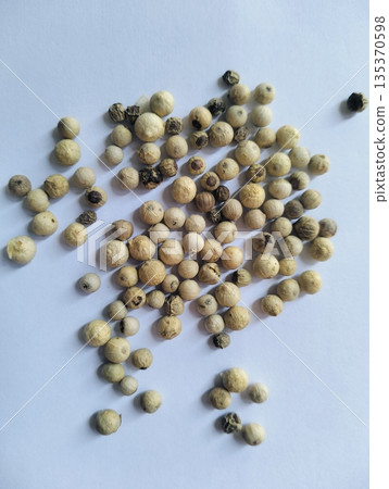 Dried white peppercorns isolated on white board with close up detail showing natural spice texture and culinary seasoning concept 135370598