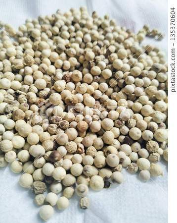 Dried white peppercorns isolated on white board with close up detail showing natural spice texture and culinary seasoning concept Dried white peppercorns isolated on white board with close up detail showing natural spice texture and culinary seasoning concept 135370604