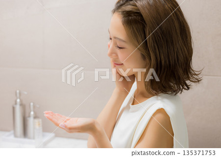 Young woman looking at a mirror 135371753