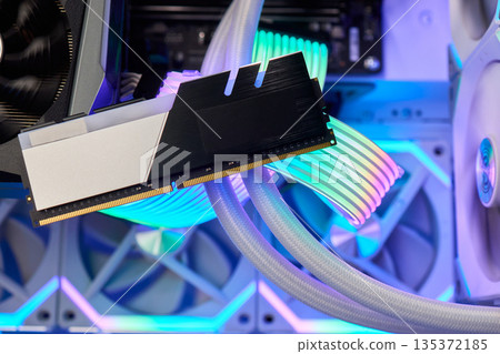 Elegant gaming hardware, High-performance RAM with cooling system, Premium illuminated memory module for gaming PCs, Sleek neon lit RAM with cooling and metallic heat sink design Elegant gaming hardware, High-performance RAM with cooling system, Premium illuminated memory module for gaming PCs, Sleek neon lit RAM with cooling and metallic heat sink design 135372185