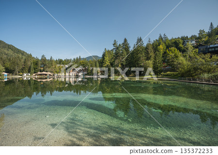 Crystal clear alpine lake in Kranjska Gora with turquoise water, forest reflections, wooden walkways and peaceful mountain scenery in the Julian Alps of Slovenia 135372233