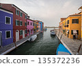 Colorful canal street on Burano island near Venice with vibrant traditional houses, small boats, calm waterway, and authentic Italian lagoon atmosphere under soft evening light 135372236