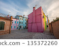 Colorful houses of Burano island near Venice showcasing vibrant pastel facades, narrow streets, and traditional Italian architecture in a quiet residential square under soft daylight sky 135372260