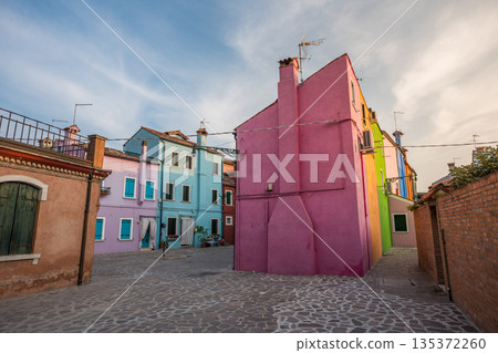 Colorful houses of Burano island near Venice showcasing vibrant pastel facades, narrow streets, and traditional Italian architecture in a quiet residential square under soft daylight sky Colorful houses of Burano island near Venice showcasing vibrant pastel facades, narrow streets, and traditional Italian architecture in a quiet residential square under soft daylight sky 135372260