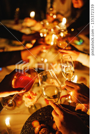 Celebration at a festive table with glasses raised Celebration at a festive table with glasses raised 135372339