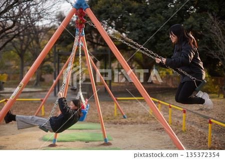 冬夜裡，兩個可愛的國中女生在公園的鞦韆上玩耍 135372354