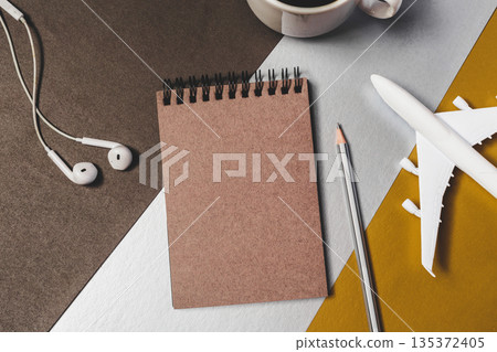 Notebook, pencil, airplane model, and coffee cup on table during work time 135372405