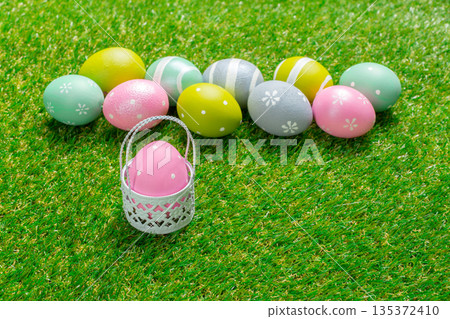 Colorful Easter eggs arranged on green grass with a small basket Colorful Easter eggs arranged on green grass with a small basket 135372410