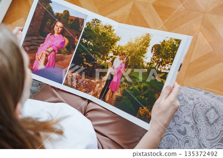 woman is holding and flipping through a photo book with a pregnancy photo shoot woman is holding and flipping through a photo book with a pregnancy photo shoot 135372492