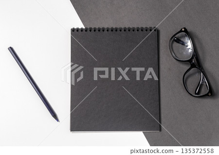 Notebook and glasses on a black and white surface in a study setting Notebook and glasses on a black and white surface in a study setting 135372558