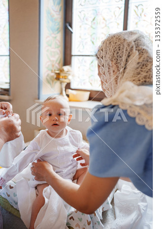 Family prepares baby for special celebration in home 135372559