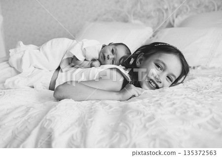 Sister and baby on bed in cozy home setting 135372563