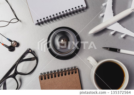 Desk scene with coffee cup, notebooks, glasses, and airplane model in workspace 135372564