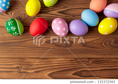 Colorful Easter eggs arranged on a wooden background for a celebration or decoration Colorful Easter eggs arranged on a wooden background for a celebration or decoration 135372565
