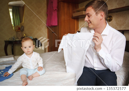 Father and baby enjoy family time while dressing 135372577