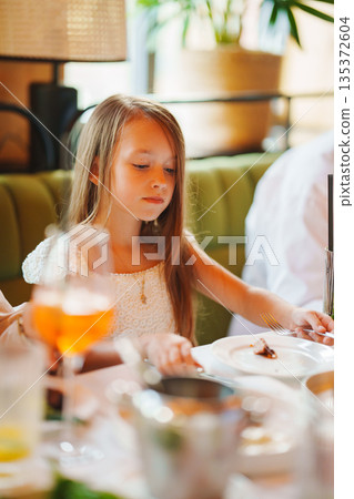 Young girl enjoying a meal at a colorful restaurant 135372604