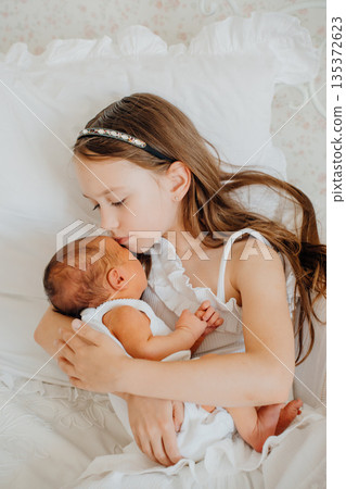 Sister holds newborn baby in quiet moment at home Sister holds newborn baby in quiet moment at home 135372623