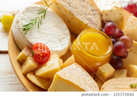 Cheese platter with honey, grapes, and cherry tomatoes on a wooden surface Cheese platter with honey, grapes, and cherry tomatoes on a wooden surface 135372688