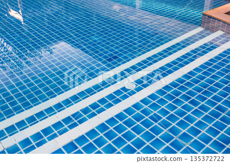 Bright blue swimming pool with tile design in warm sunny weather 135372722