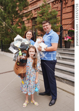 Family celebrates new member outside brick building Family celebrates new member outside brick building 135372738