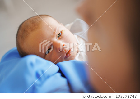 Newborn gazes at caregiver with soft expression Newborn gazes at caregiver with soft expression 135372748
