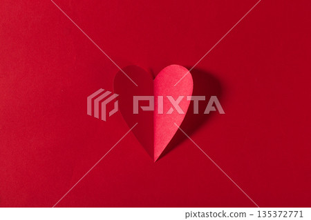 Heart shape made of paper on a red background during daytime in a simple setting Heart shape made of paper on a red background during daytime in a simple setting 135372771