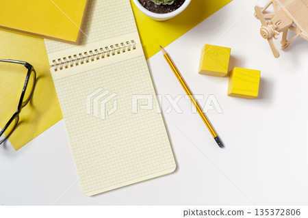 Notepad and stationery items on a white surface with yellow accents in the workspace Notepad and stationery items on a white surface with yellow accents in the workspace 135372806