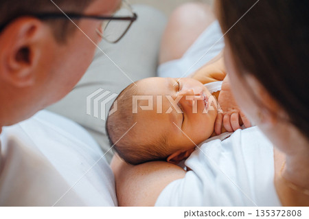 New parents hold their baby close in a home setting 135372808