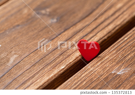 Red heart sits on wooden surface with natural light during daytime Red heart sits on wooden surface with natural light during daytime 135372813