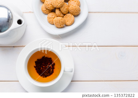 Enjoying tea and cookies on a white wooden table during afternoon break time 135372822